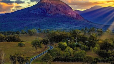 A winding road through a green landscape with a mountain in the background.