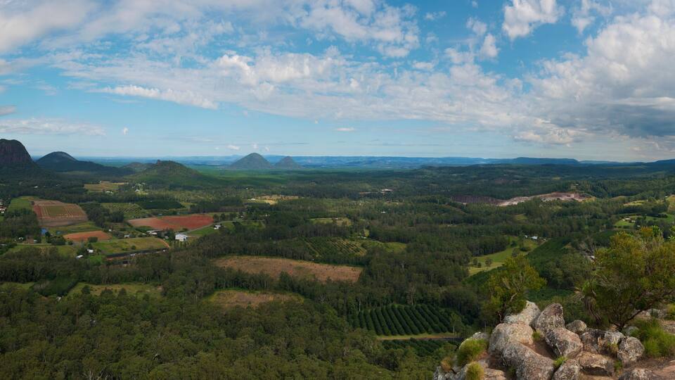 A mountainous landscape with a village, rolling hills, and a clear sky.