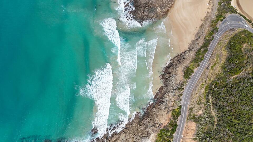 A coastal road with a beach and rocky cliffs.
