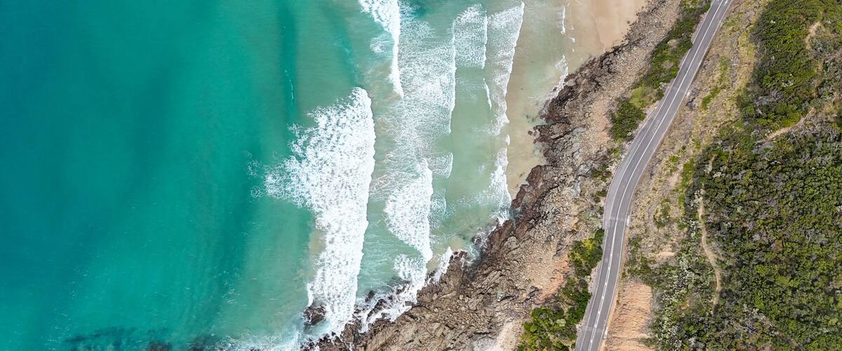 A coastal road with a beach and rocky cliffs.