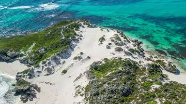 Paisagem costeira com praias de areia branca, águas turquesa cristalinas e vegetação exuberante.