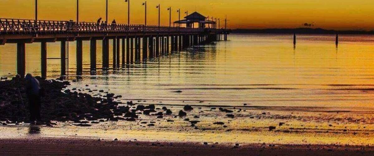 A pier extending into calm waters at sunset.
