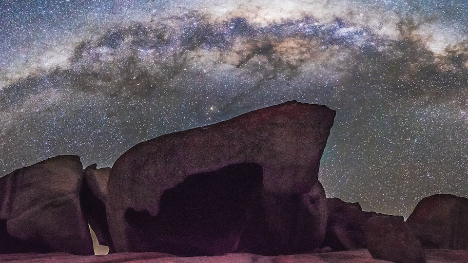 A starry night sky with the Milky Way over rock formations.