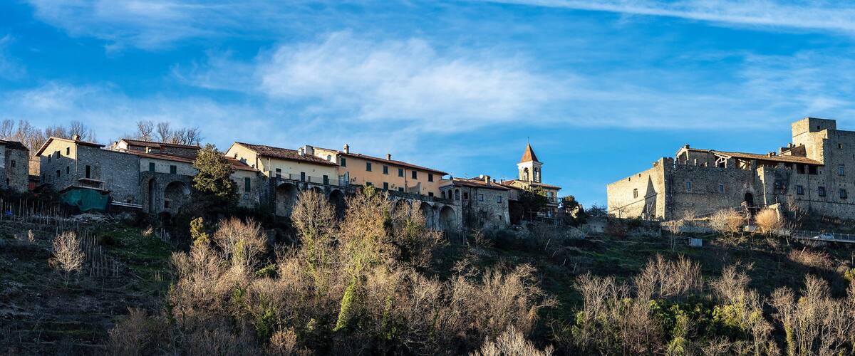 A historic town with medieval architecture, including a prominent tower and a bridge connecting buildings.