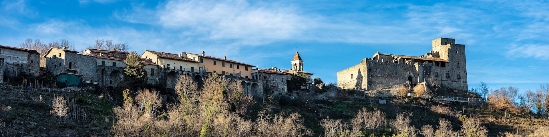 A historic town with medieval architecture, including a prominent tower and a bridge connecting buildings.