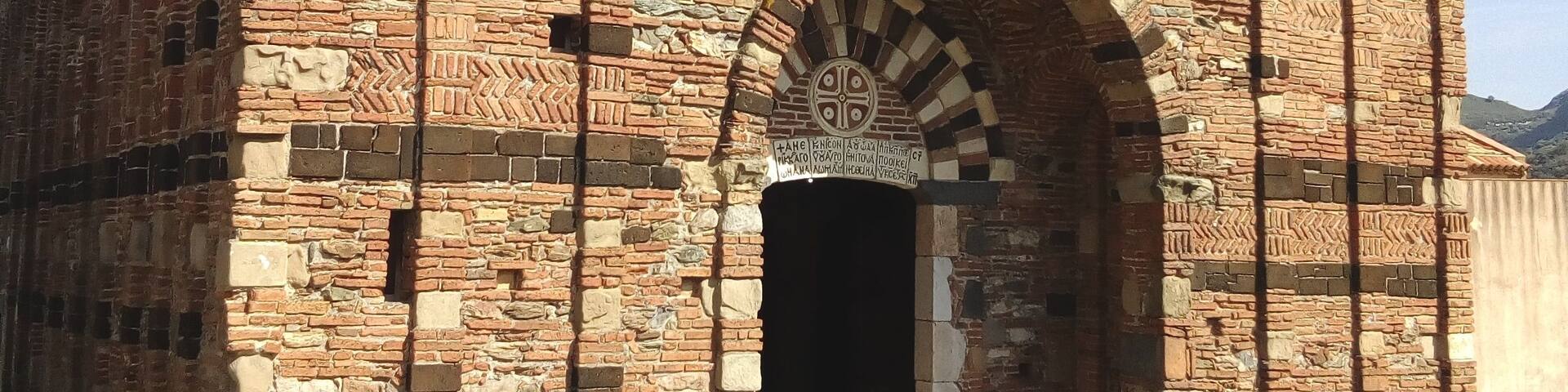 An ancient brick building with arched doorways and a small window.