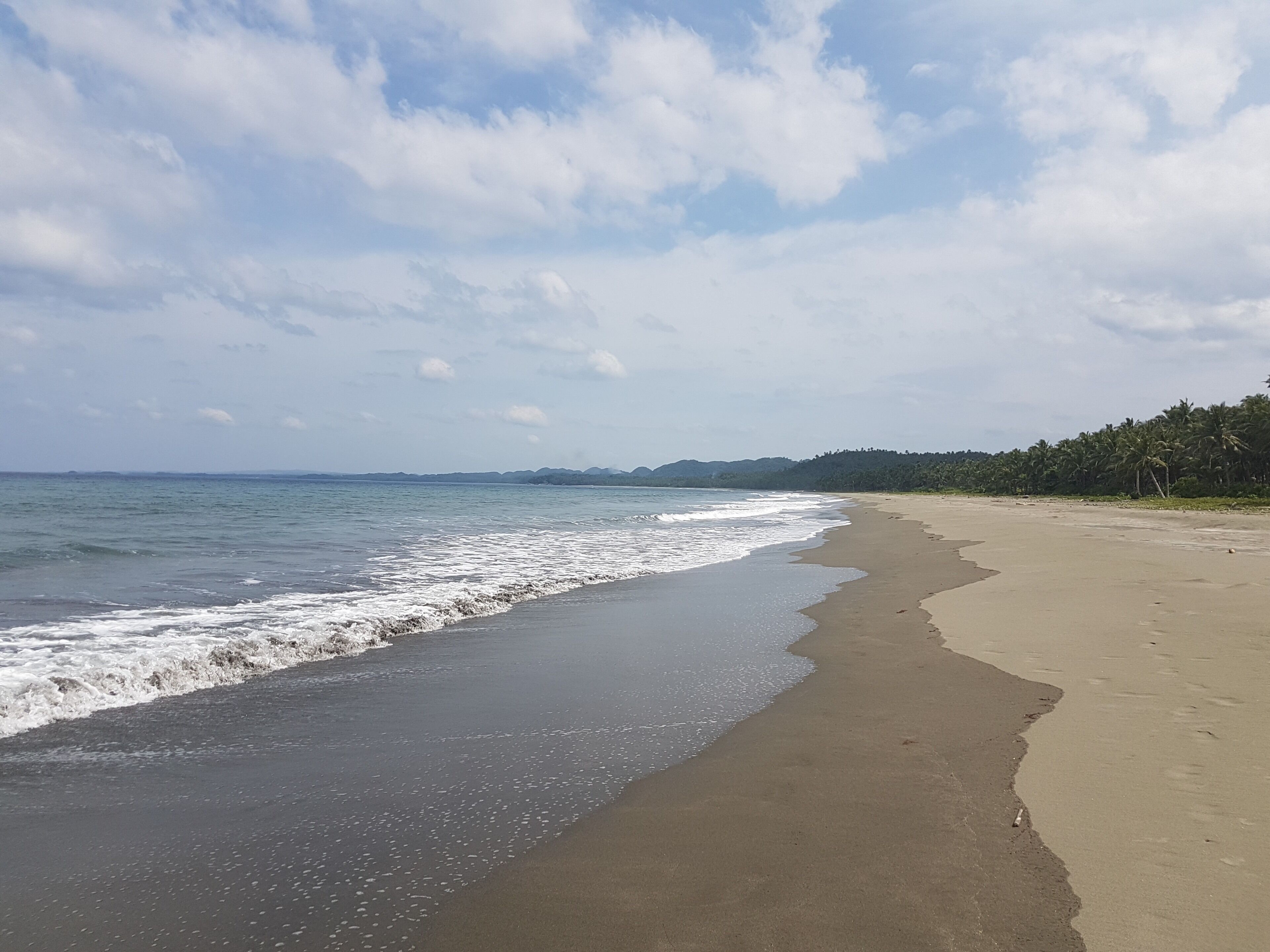 A beach with a sandy shore and gentle waves.