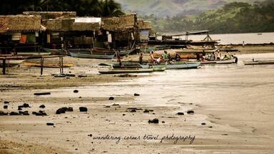 Une plage avec des bateaux, des cabanes et des palmiers.
