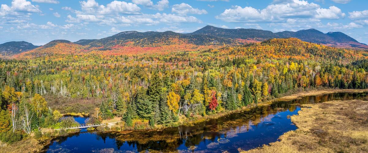 A mountainous landscape with autumn foliage and a calm river.