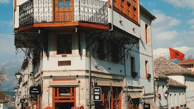 A traditional two-story building with a balcony, wooden shutters, and a sign that reads "Old Well".