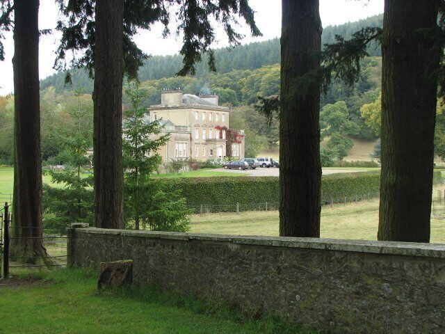 A large building surrounded by trees and a stone wall.