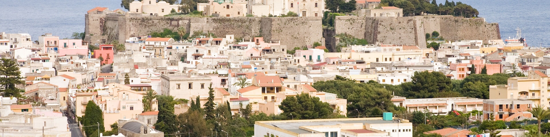 A coastal town with historic fortifications, a prominent church, and dense residential buildings.