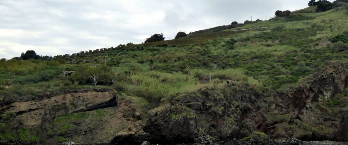 A river with a rocky shoreline and a grassy hill in the background.