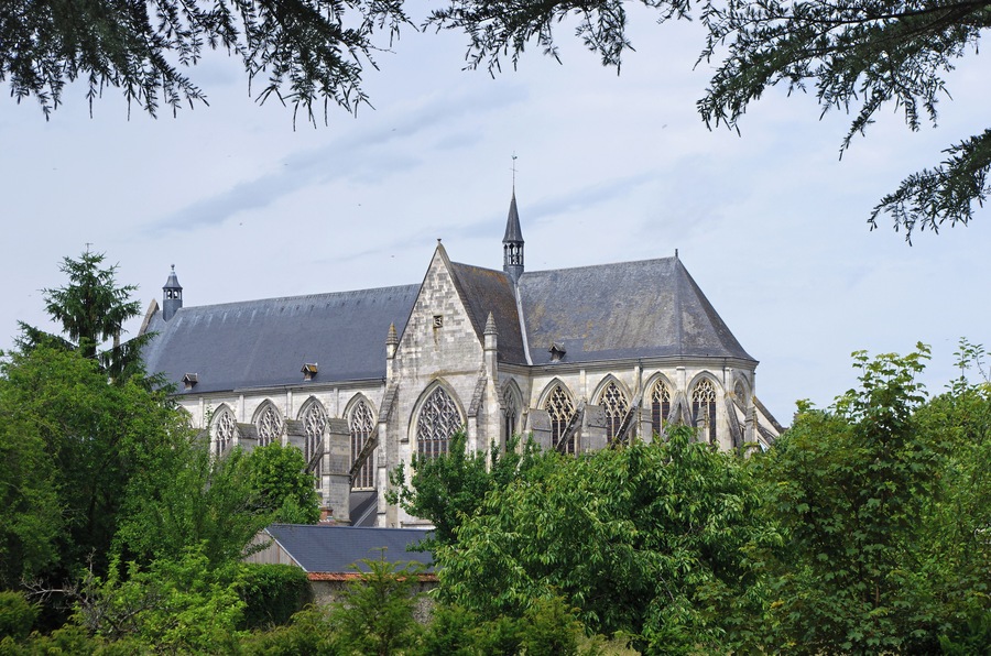 A Gothic-style church with a prominent tower and arched windows, surrounded by lush greenery.