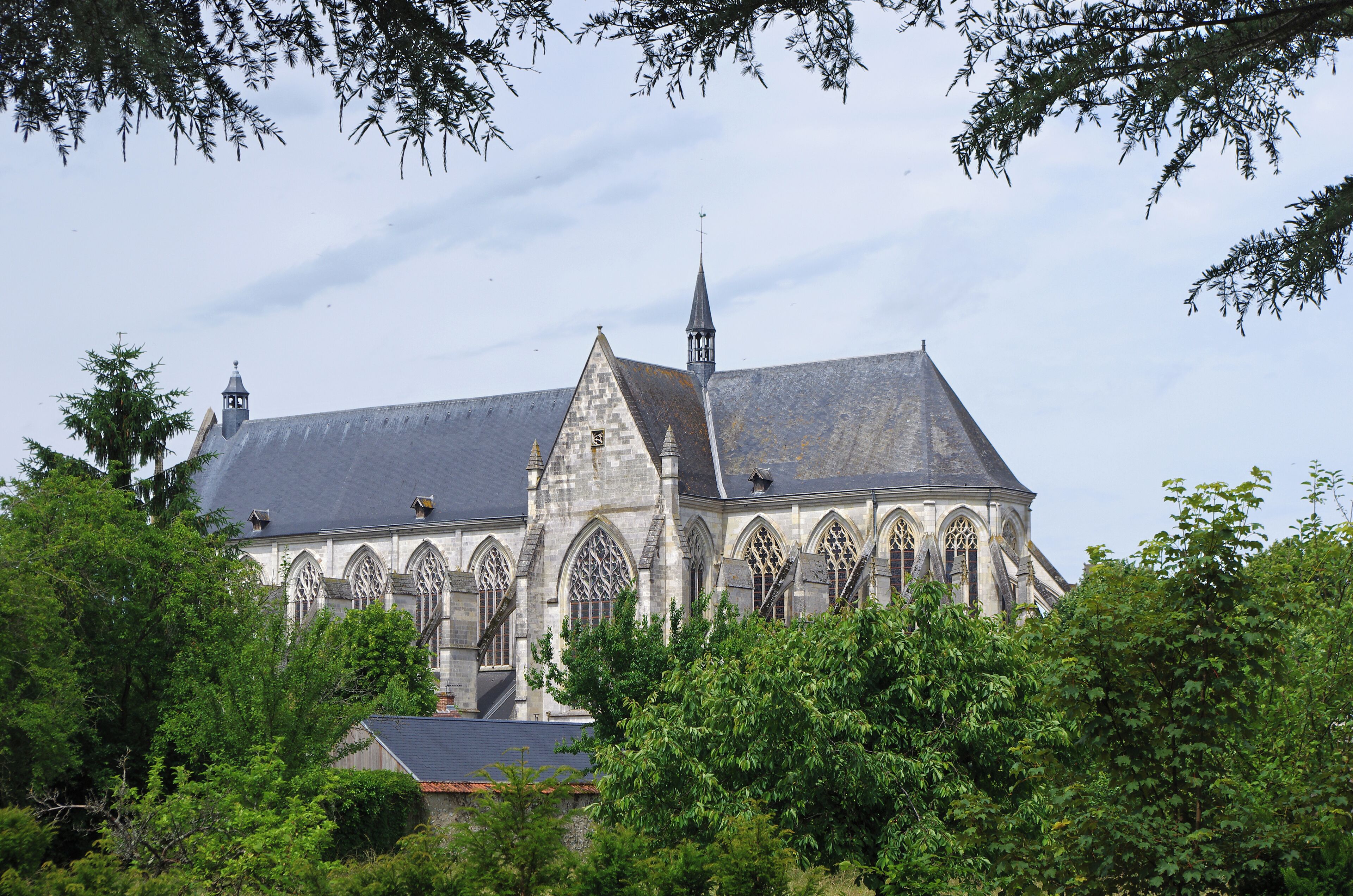 A Gothic-style church with a prominent tower and arched windows, surrounded by lush greenery.