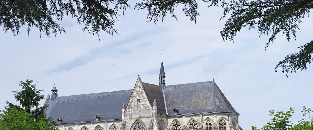 A Gothic-style church with a prominent tower and arched windows, surrounded by lush greenery.