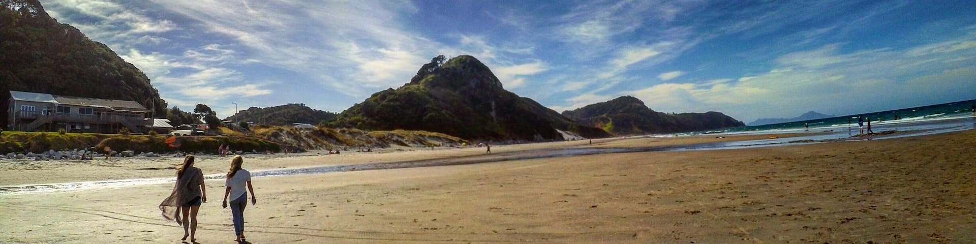 A beach with footprints, a rainbow, and mountains in the background.