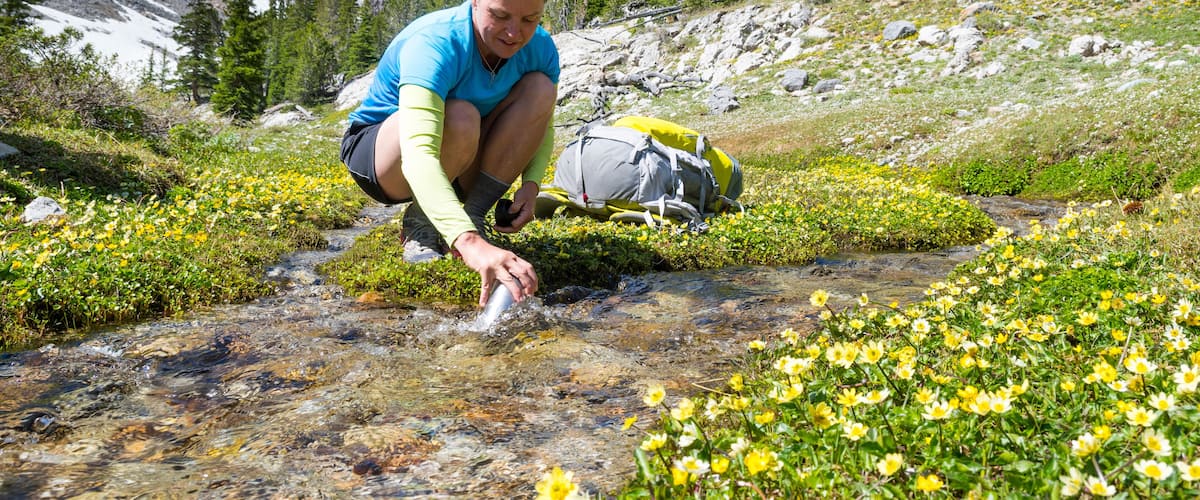 Woman filling bottle with water from stream, Merriam Lake Basin, Upper†Pashimeroi†Valley, Lost River Range, Challis, Idaho, USA
