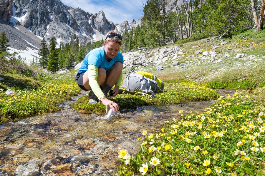 Woman filling bottle with water from stream, Merriam Lake Basin, Upper†Pashimeroi†Valley, Lost River Range, Challis, Idaho, USA