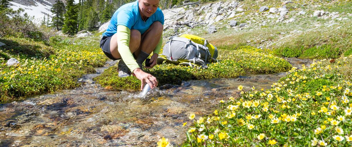 Woman filling bottle with water from stream, Merriam Lake Basin, Upper†Pashimeroi†Valley, Lost River Range, Challis, Idaho, USA