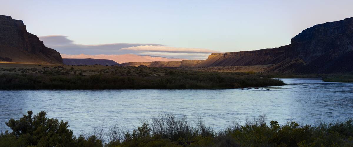 A river flowing through a canyon with steep cliffs on either side.