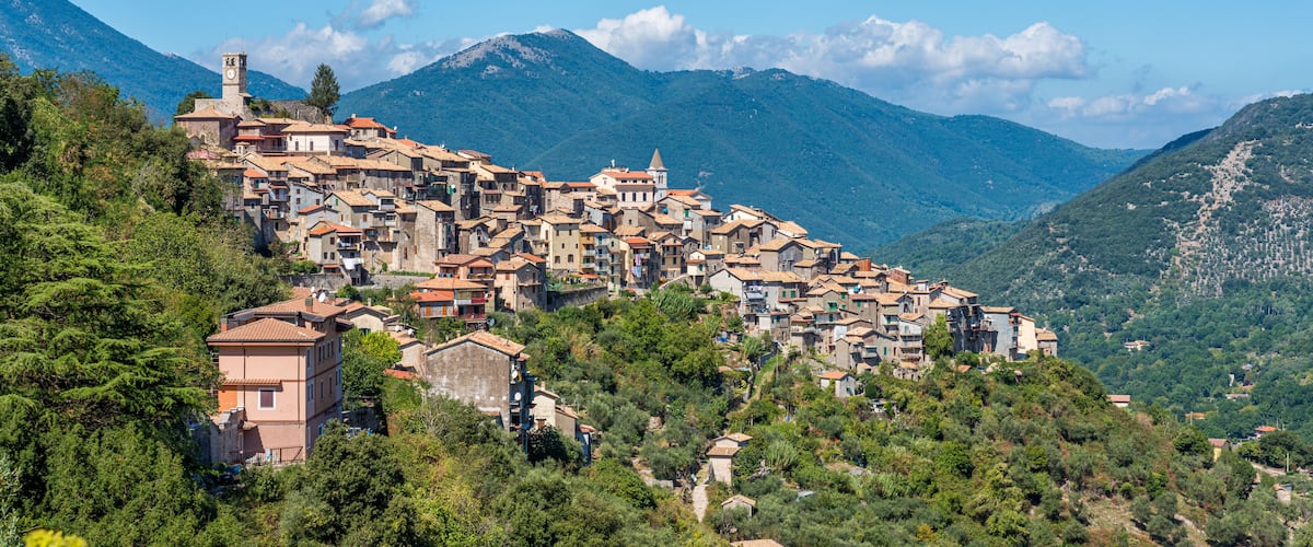 A hillside village with traditional architecture, surrounded by lush greenery and mountains.