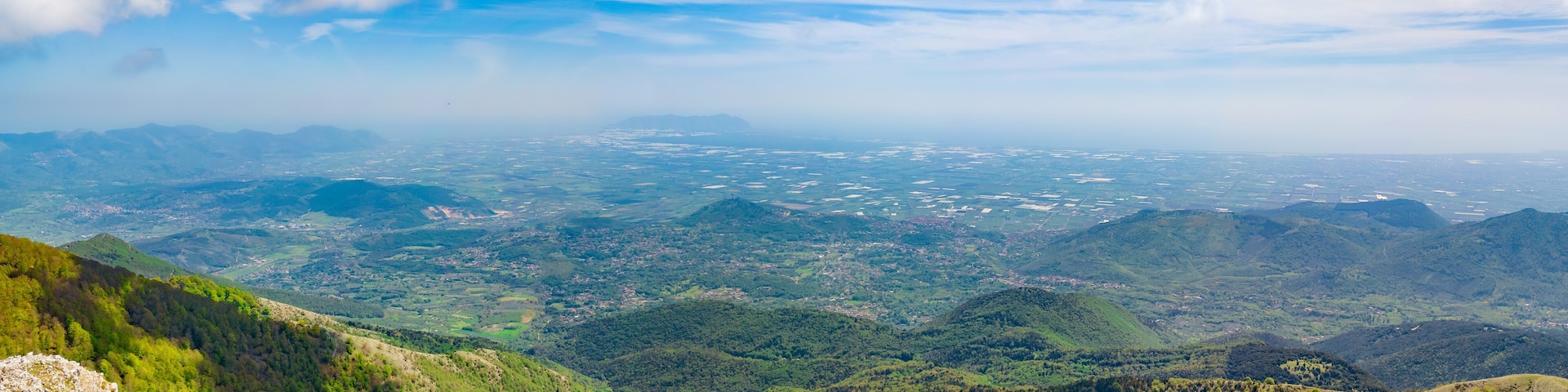 Un paisaje montañoso con un valle y una ciudad distante.