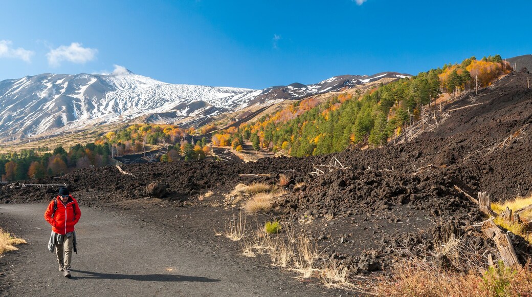 Mount Etna, Italy: panorama of the northern side of the volcano and a hiker walking on a lavic pathway