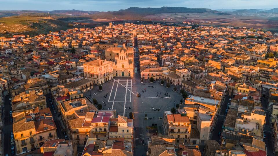 A panoramic view of a densely packed town with a prominent square and a large church in the center.