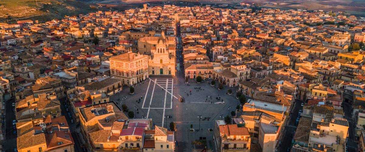 A panoramic view of a densely packed town with a prominent square and a large church in the center.