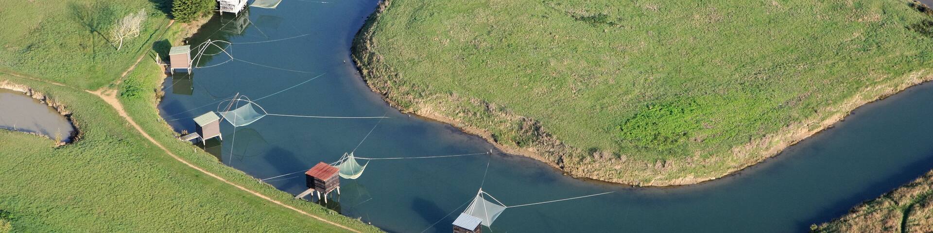 An aerial view of a river with houses and fishing nets along its banks.