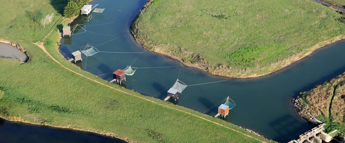 An aerial view of a river with houses and fishing nets along its banks.