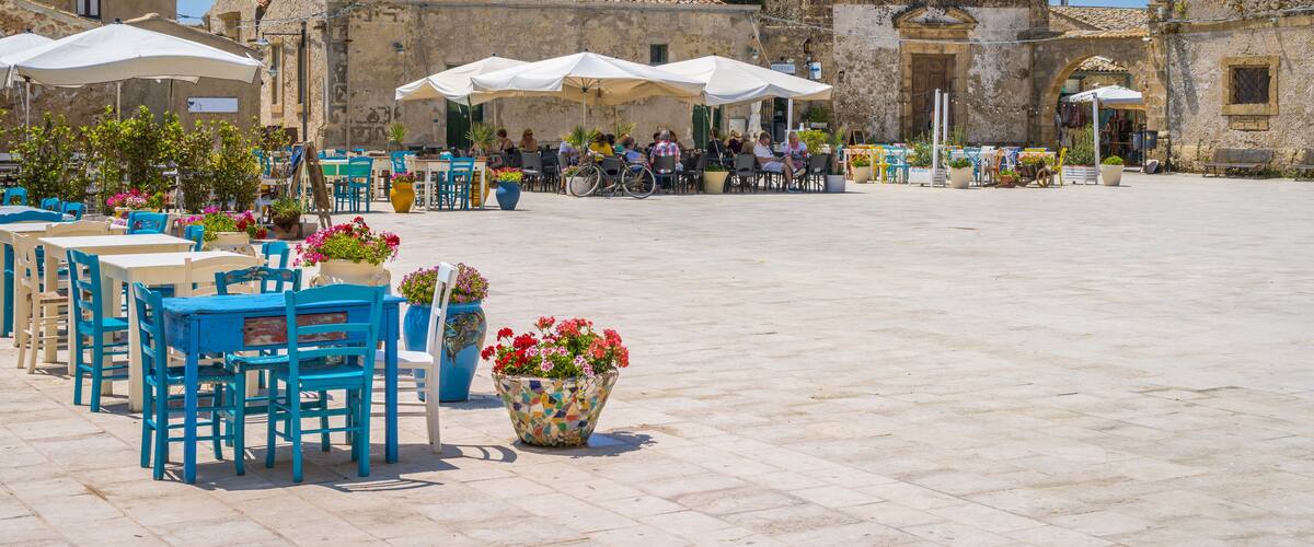 A plaza with outdoor seating, a historic church, and a clear blue sky.