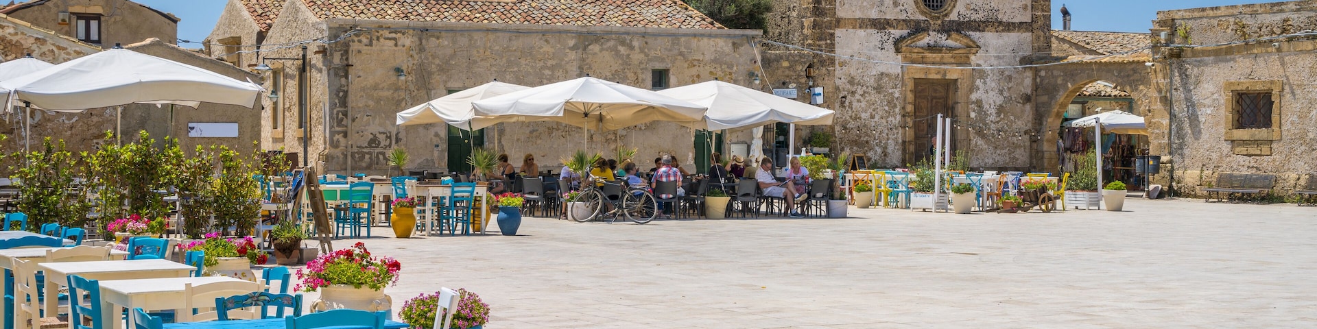 A plaza with outdoor seating, a historic church, and a clear blue sky.