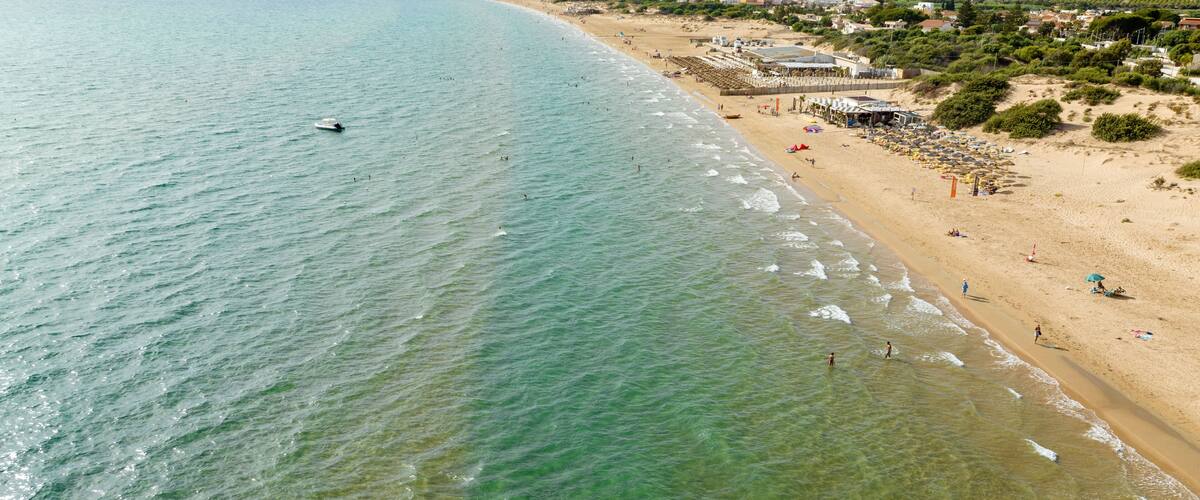 Aerial view of a sandy beach overlooking the Mediterranean Sea. This is the beach of Santa Maria del Focallo, a small tourist and coastal town in the municipality of Ispica, in Sicily, Italy.