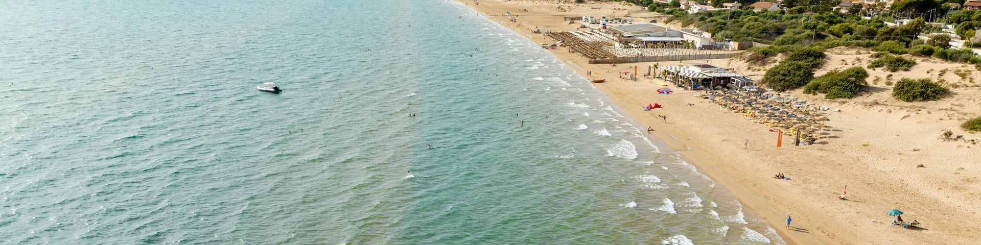 Aerial view of a sandy beach overlooking the Mediterranean Sea. This is the beach of Santa Maria del Focallo, a small tourist and coastal town in the municipality of Ispica, in Sicily, Italy.
