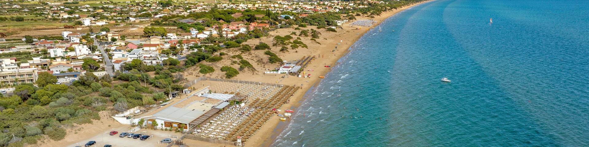 Aerial view of a sandy beach overlooking the Mediterranean Sea. This is the beach of Santa Maria del Focallo, a small tourist and coastal town in the municipality of Ispica, in Sicily, Italy.