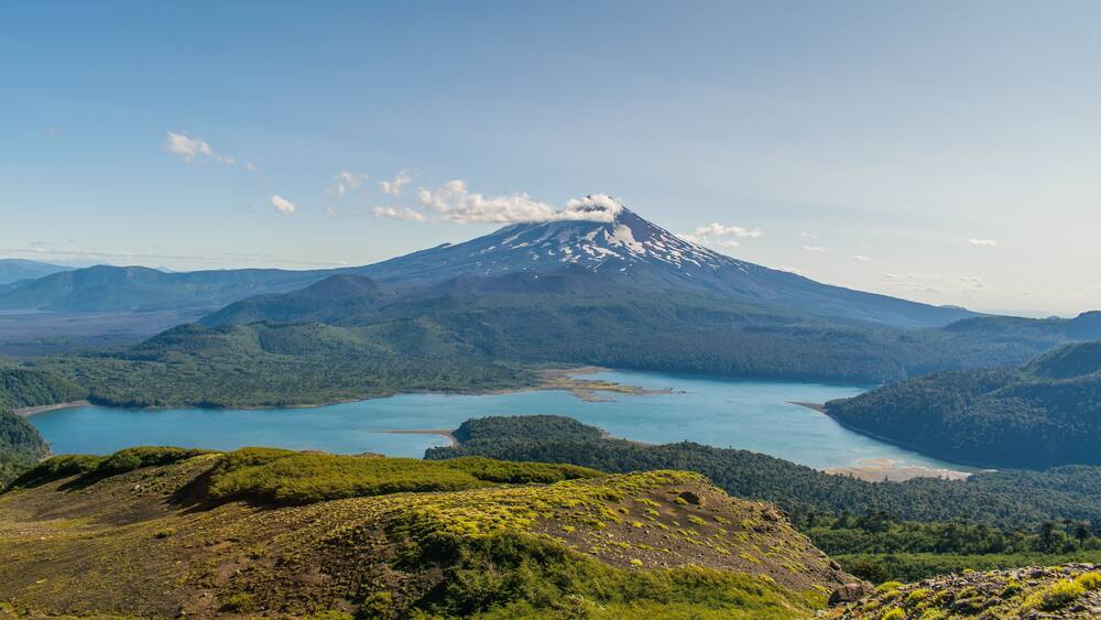 A mountain with a lake at its base and a forested valley.