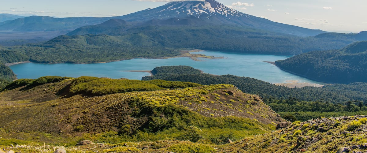 Una montaña con un lago a su base y un valle cubierto de bosque.