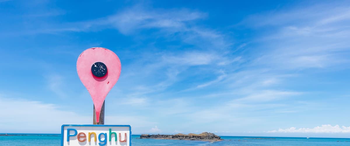 A beach with a sign reading "Penghu" and a rocky shoreline.