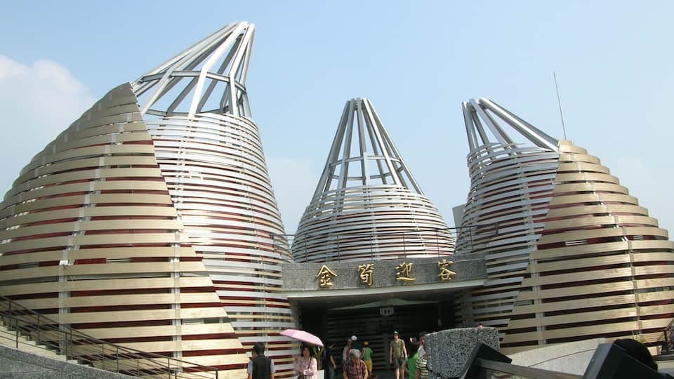 A modern architectural structure with three large, cylindrical buildings with slatted roofs.