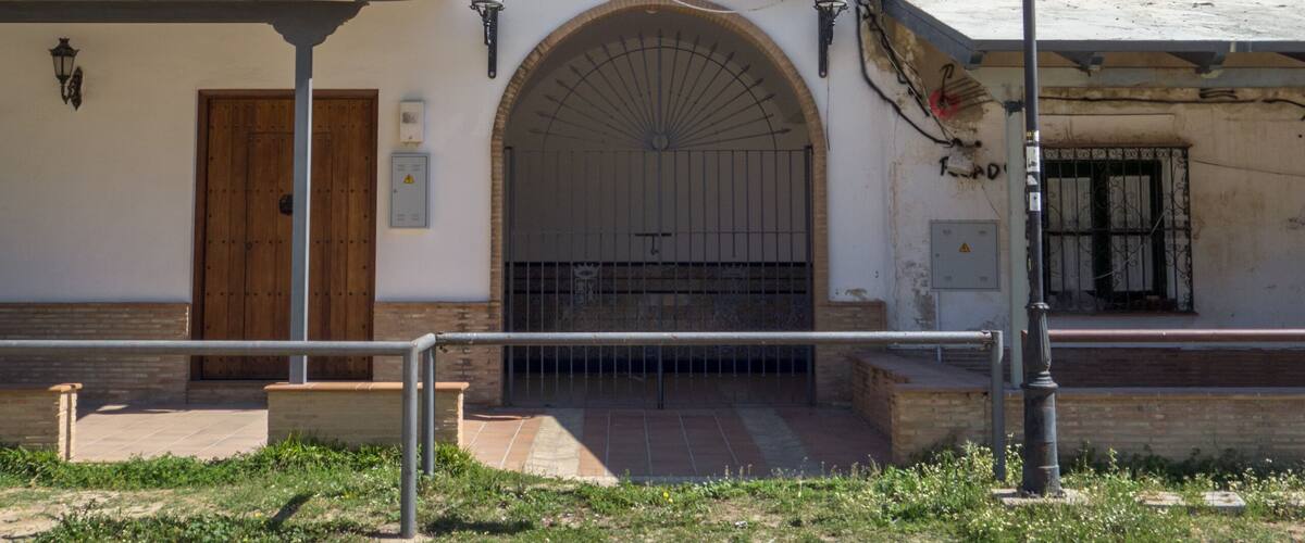 A white building with a bell tower, a wooden door, and a sign that reads "Espartinas 1940".