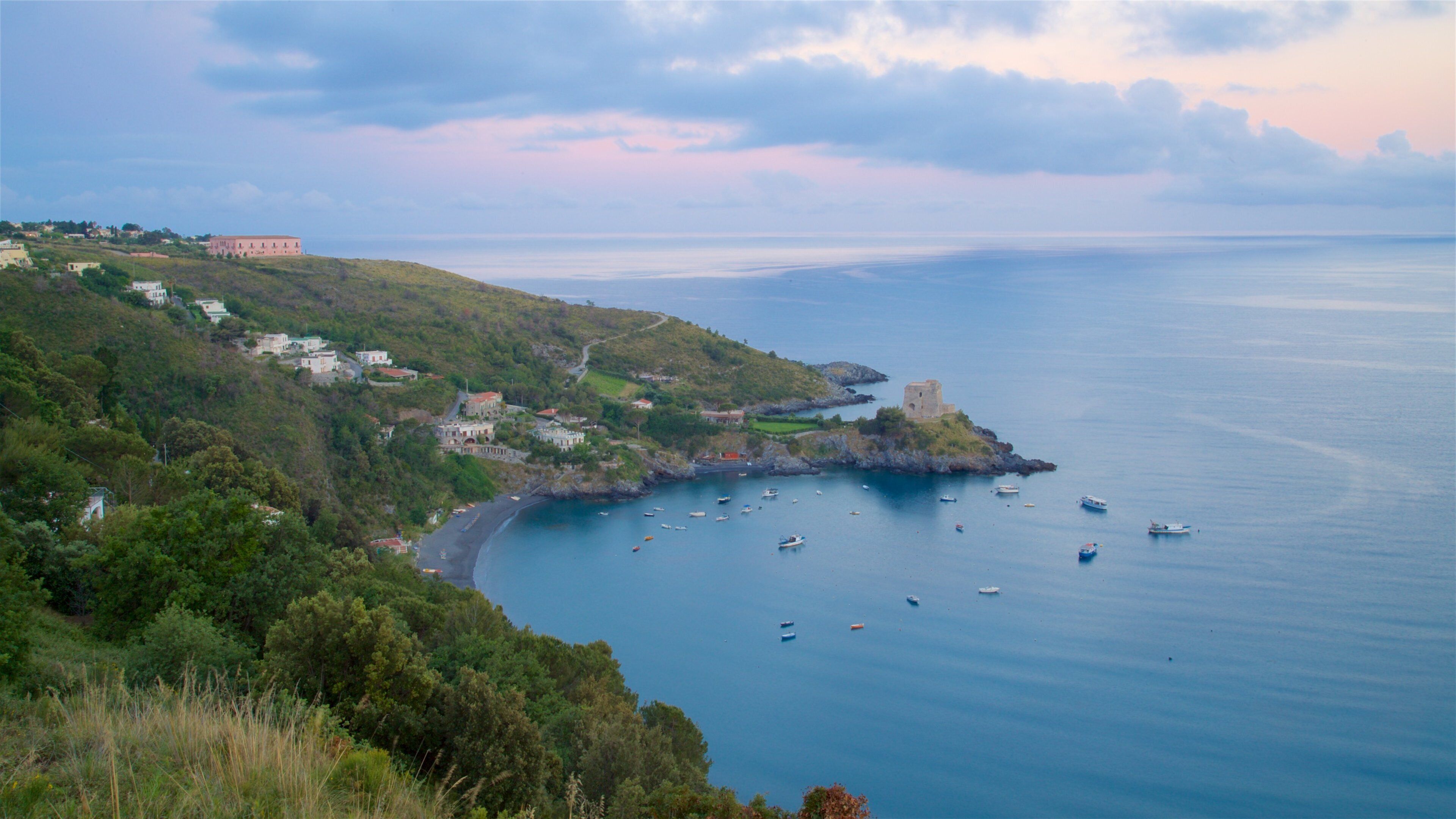 A coastal landscape with a bay, boats, and buildings on a hillside.
