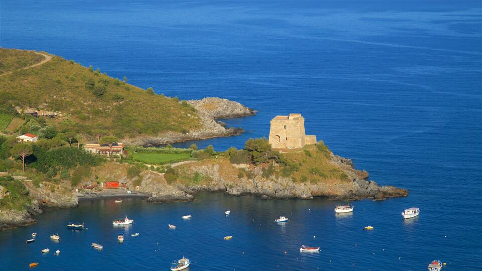 A coastal landscape with a historic stone tower, a small church, and several boats in the water.