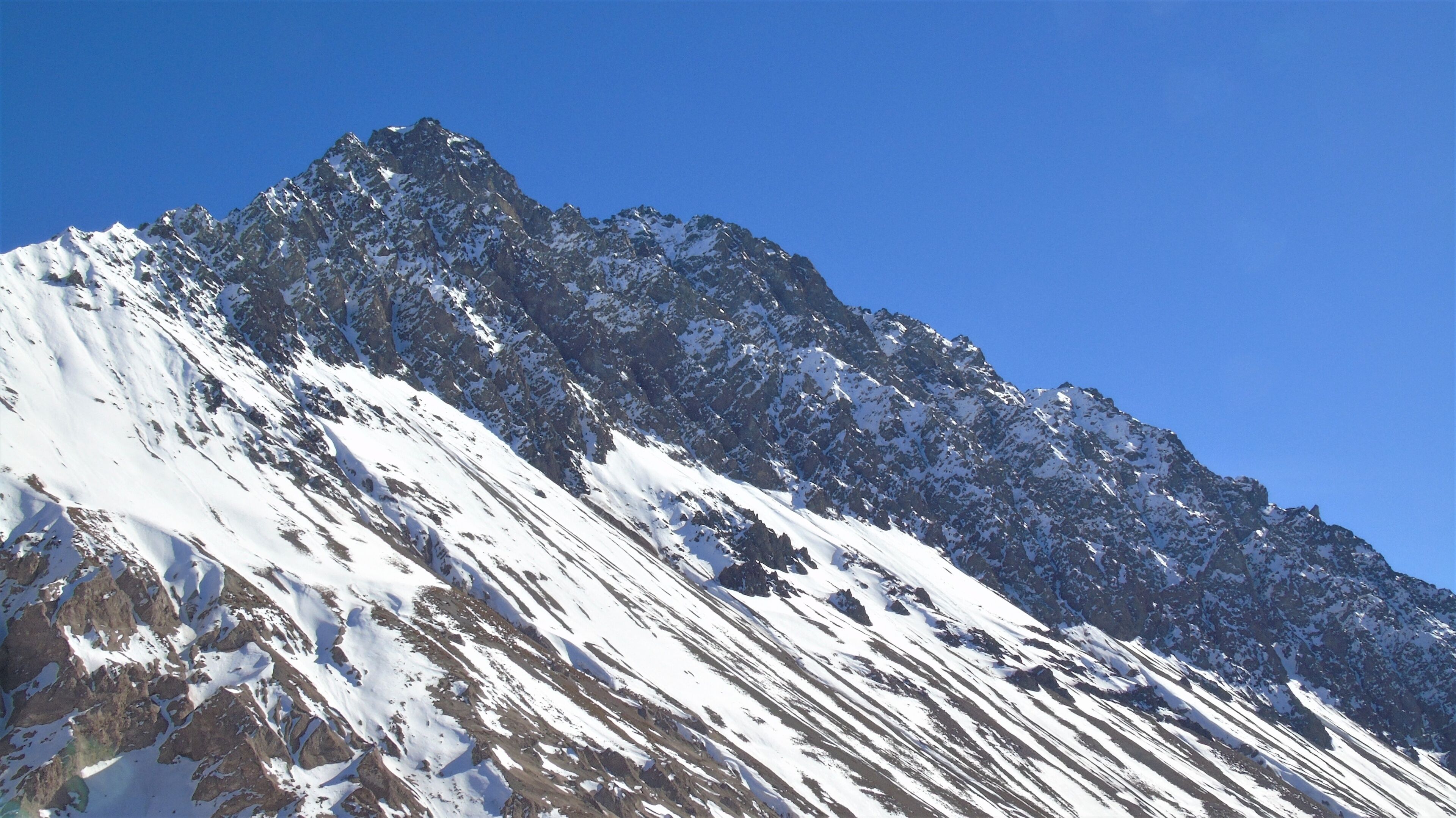 A snow-covered mountain peak under a clear blue sky.