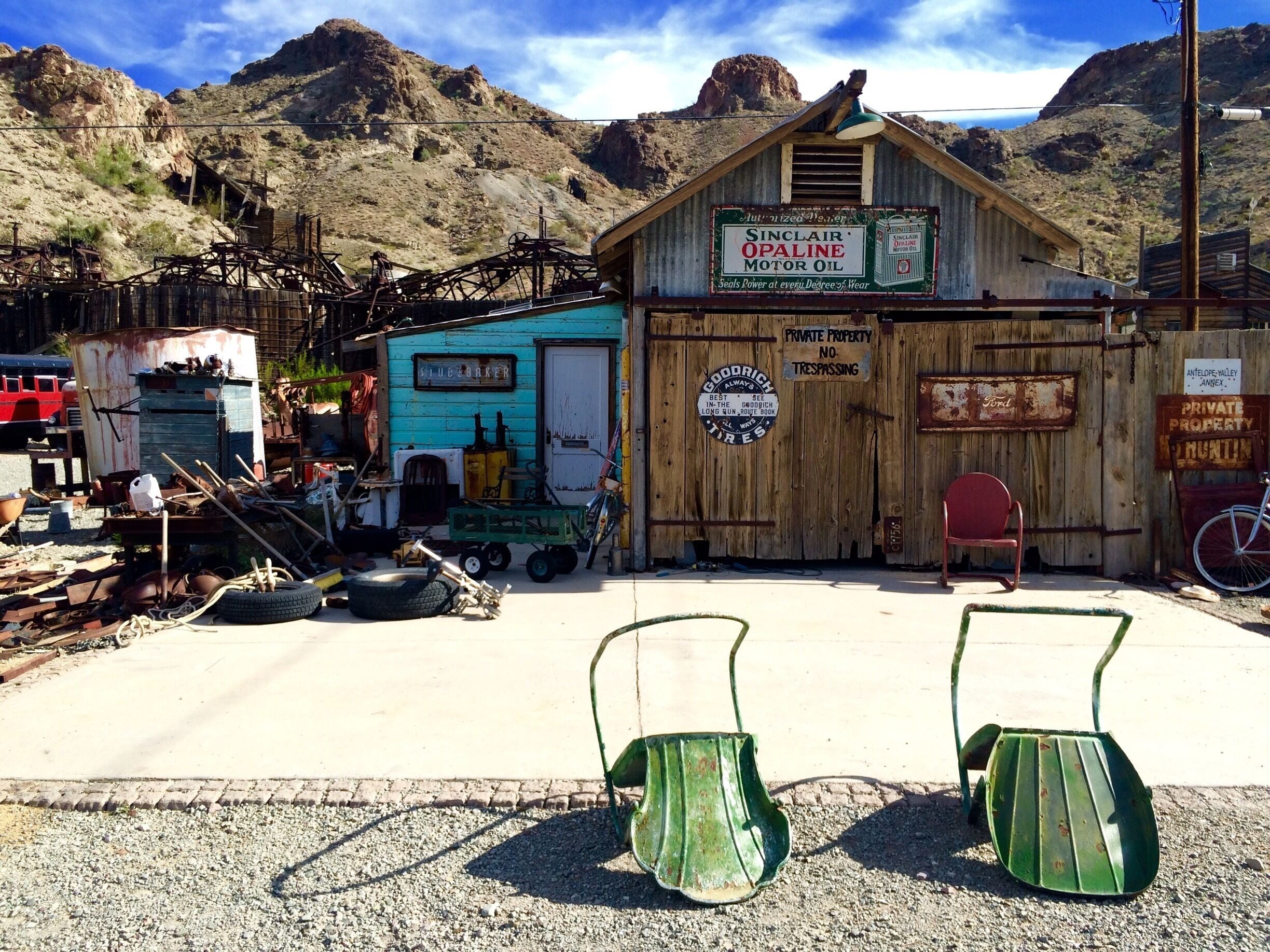 A rustic building with a sign for Sinclair Opaline Motor Oil, surrounded by a mountainous landscape.