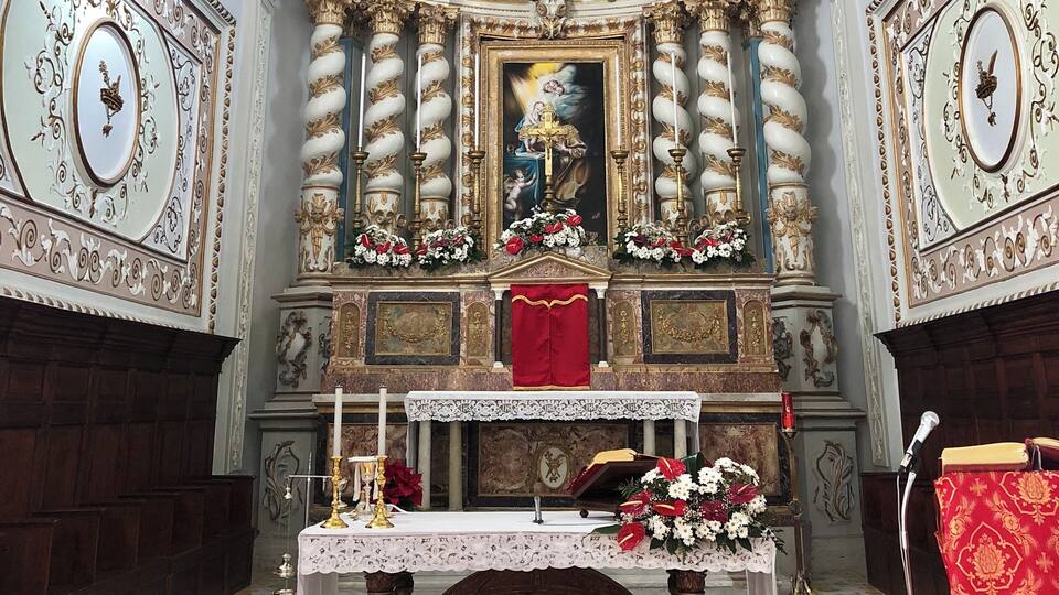 An ornate church interior with a high ceiling, elaborate decorations, and a central altar.