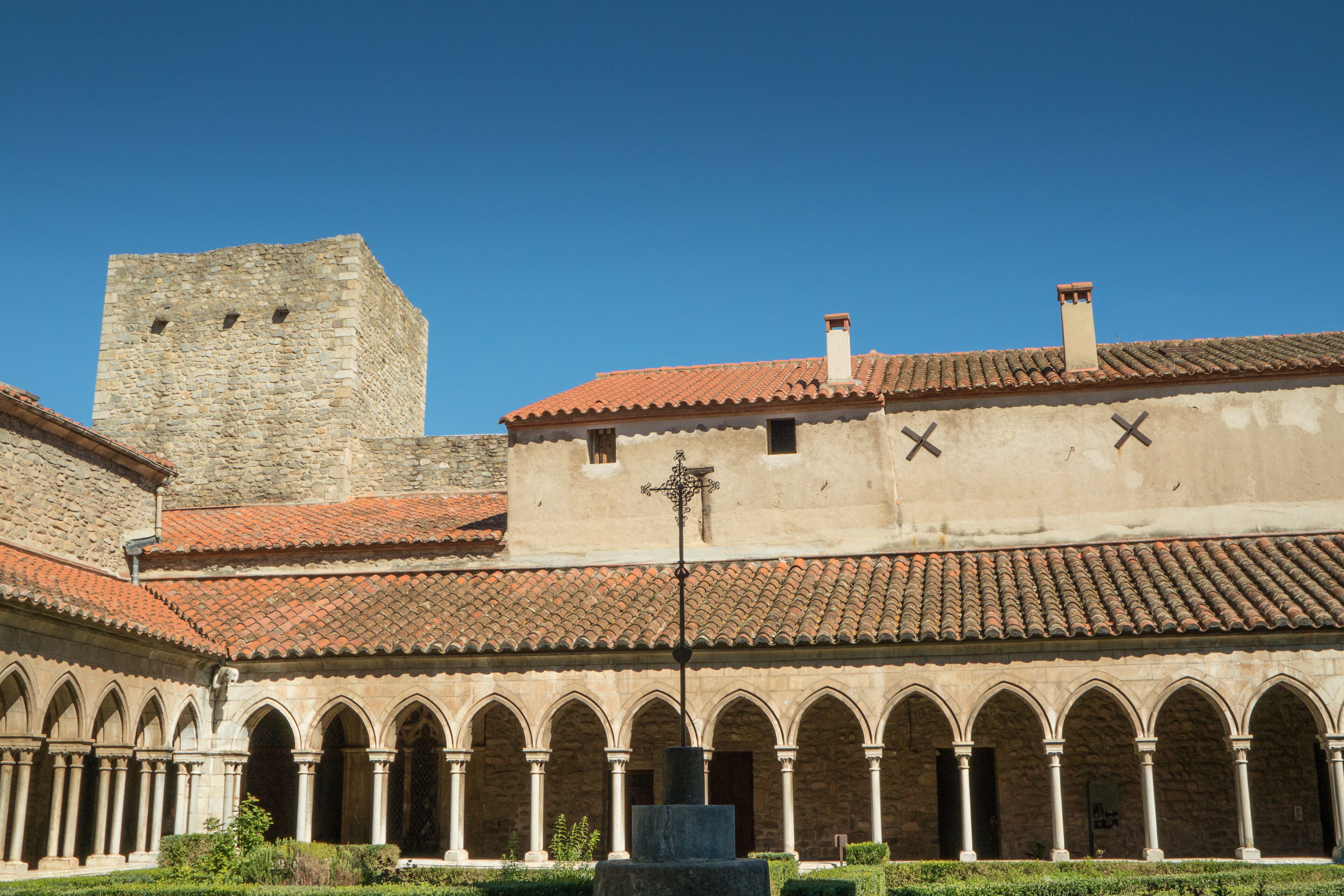 A historic building with a courtyard, a tower, and a cross on the roof.