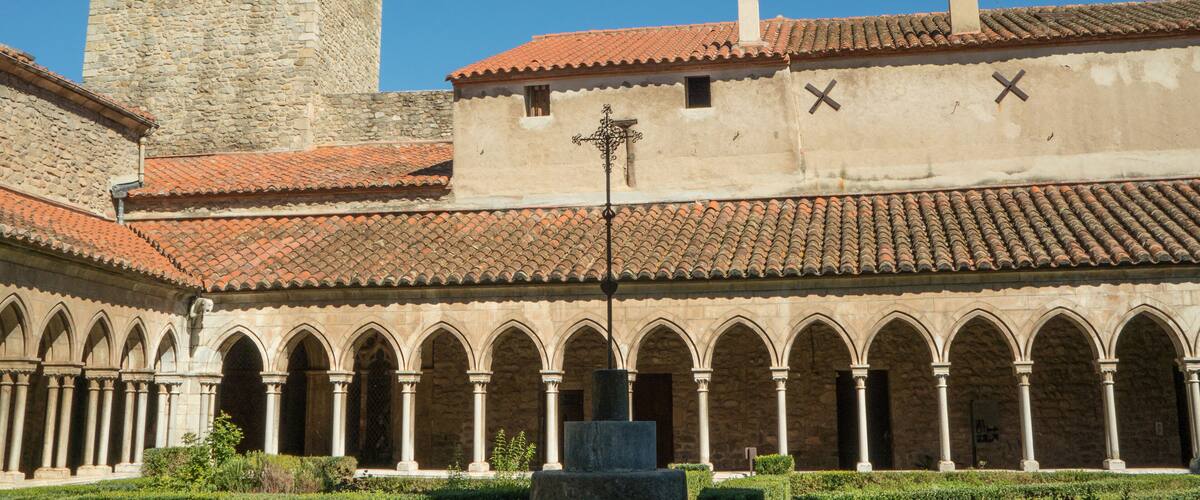 A historic building with a courtyard, a tower, and a cross on the roof.