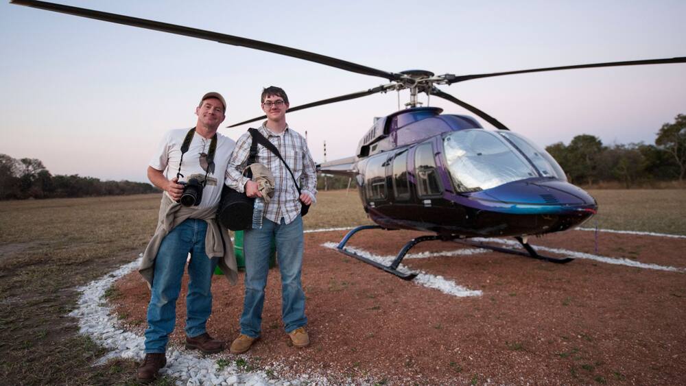 Male photographer and his son arrive by helicopter at Chitengo Camp inside Gorongosa National Park, Mozambique; Gorongosa National Park, Mozambique